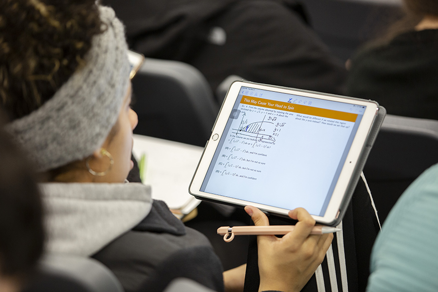 A student uses a tablet to take notes during a math class.